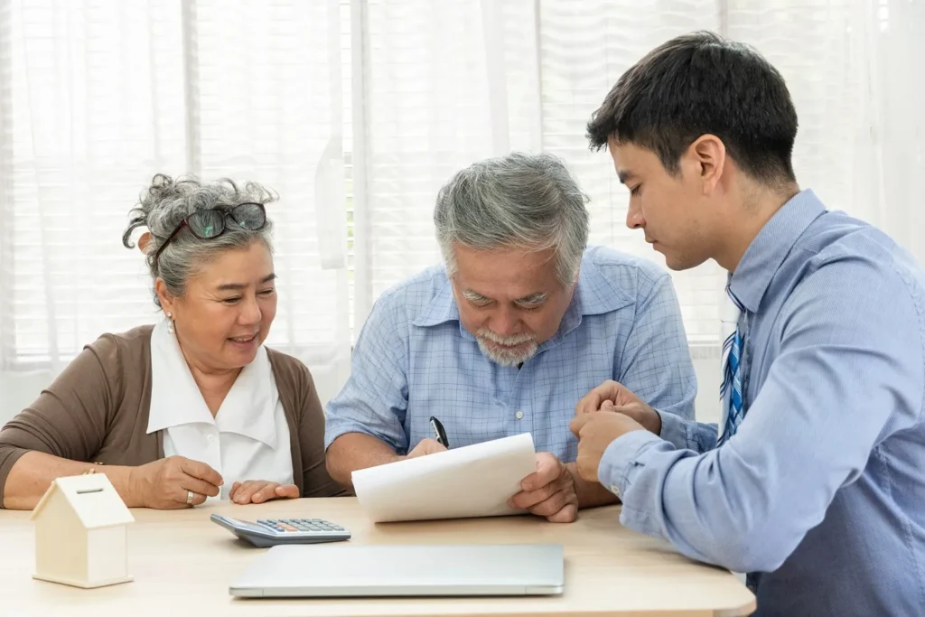 An elder couple sign estate planning documents with their lawyer.