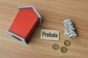 Small wooden model home, a roll of dollar bill tagged with the word Probate, and three coins on a desk.