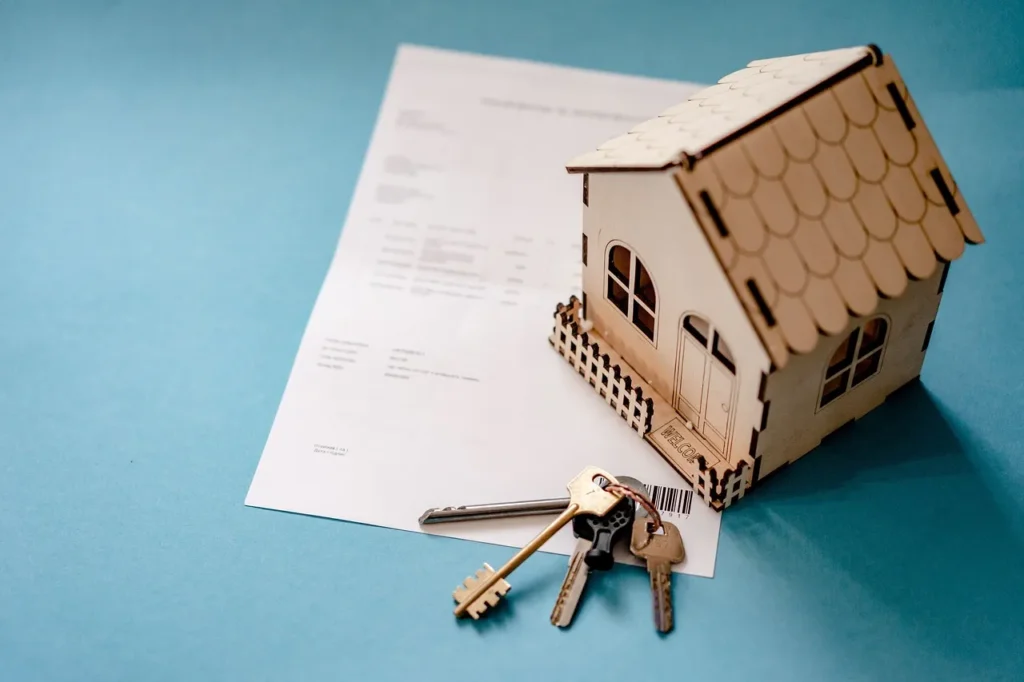 A mini wooden house sitting on a piece of paper with keys.