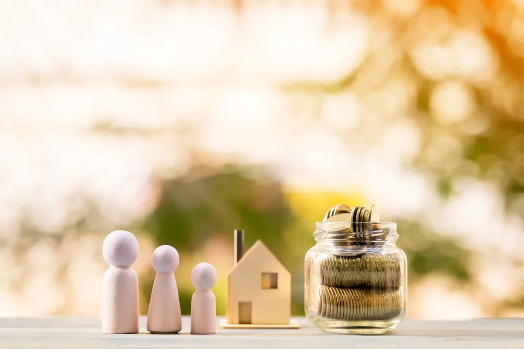 A wooden family, little house and a jar full of coins.