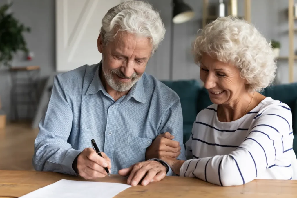 An elderly couple signing paperwork.