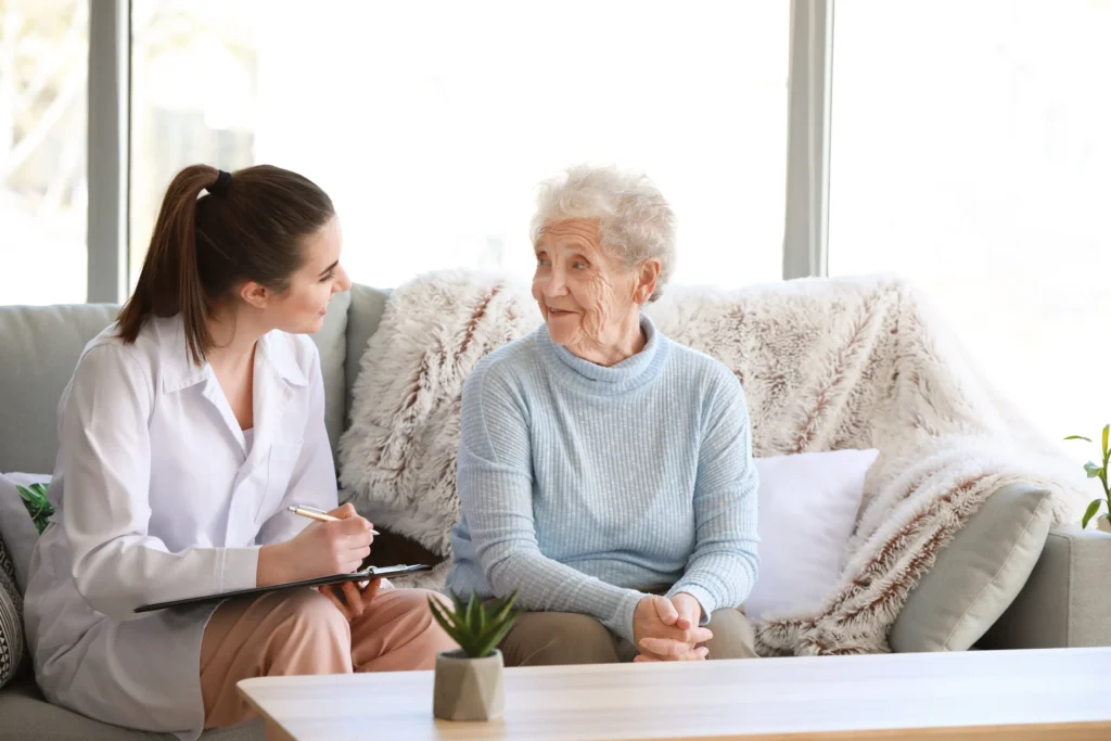 An elderly woman and her care giver sitting on couch.