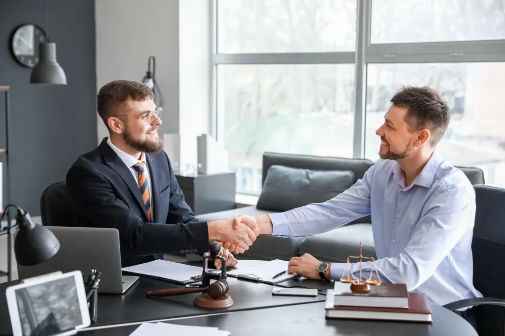 A lawyer and client shake hands in the lawyers office.