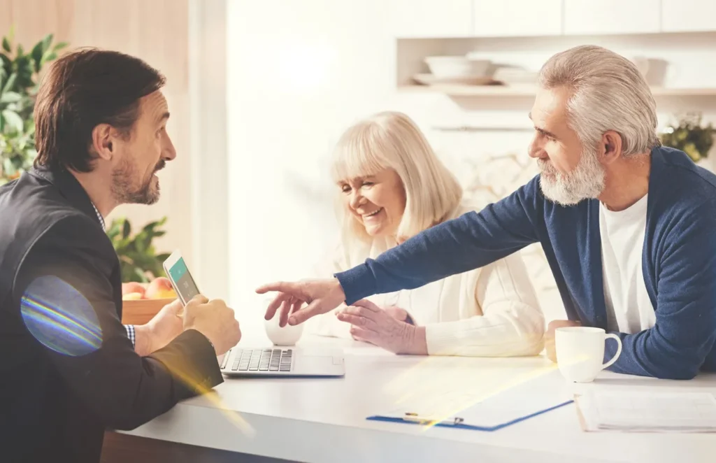 An attorney speaking with his clients showing them something on his computer.