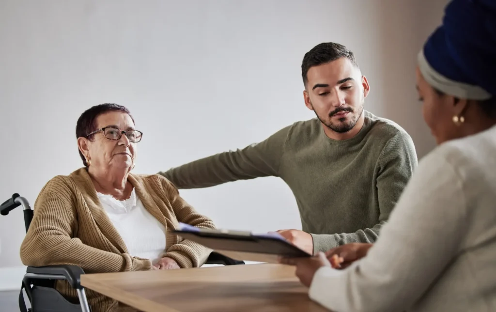 An elderly woman in a wheelchair and a young male relative meeting with a trust attorney.